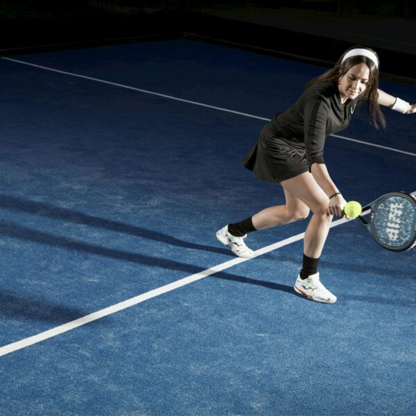 a young woman holding a tennis racquet on a tennis court