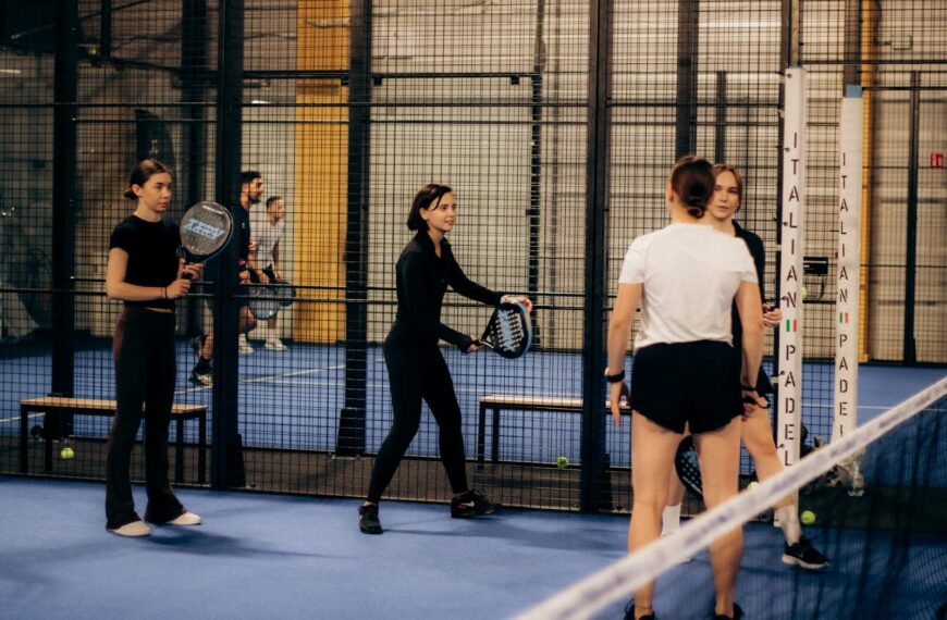 Indoor padel tennis game with multiple players preparing for a match.